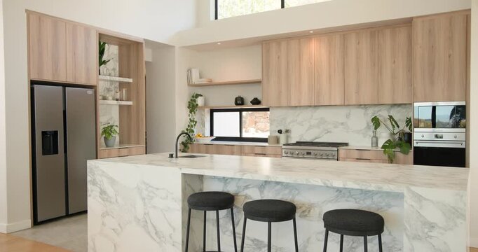 Camera is pulling back and tilting up revealing marble island with 3 stools showing kitchen layout