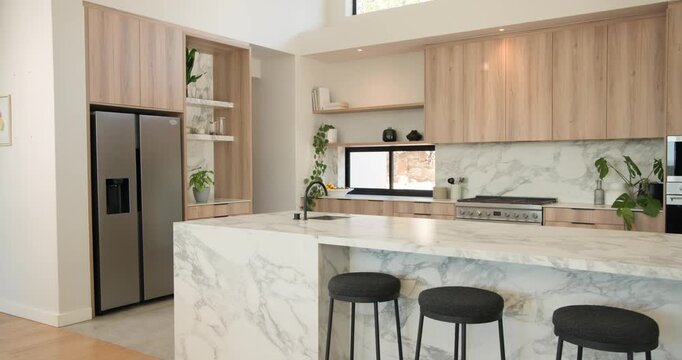 Camera is starting wide and panning across marble kitchen island, revealing sink and showing range