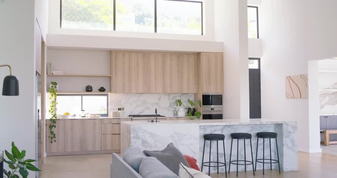 Camera steadying then panning out showing marble island, sofa, tall windows, cabinets