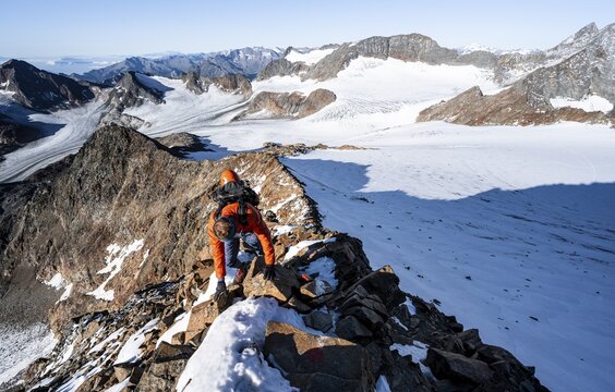 Mountaineer climbing on a rocky ridge on the mountain peak Wilder Freiger, in the background Signal summit and summit of Becher with Becherhaus, picturesque high mountain landscape, view of glacier &Uuml;beltalferner and rocky mountain peaks K&ouml;nigshofspitz and Sonklarspitze, Stubai Alps, South Tyrol, Italy