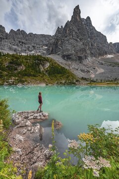 Young woman, hiker at the turquoise-green Sorapis lake, Lago di Sorapis, mountain peak Dito di Dio, Dolomites, Belluno, Italy