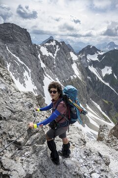 Mountaineer on a secured ridge trail with remnants of snow, mountain panorama, dramatic cloudy sky, Heilbronner Weg, Allg&auml;u Alps, Allg&auml;u, Bavaria, Germany