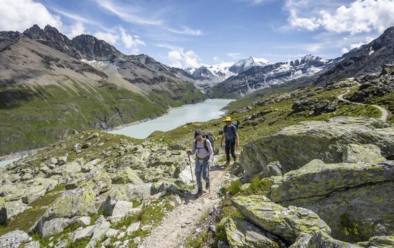 Two mountaineers on a hiking trail, view of a blue mountain lake, Lac des Dix reservoir, mountain peak Mont Blanc de Cheilon in the background, H&eacute;rm&eacute;nence, Valais Alps, Valais, Switzerland