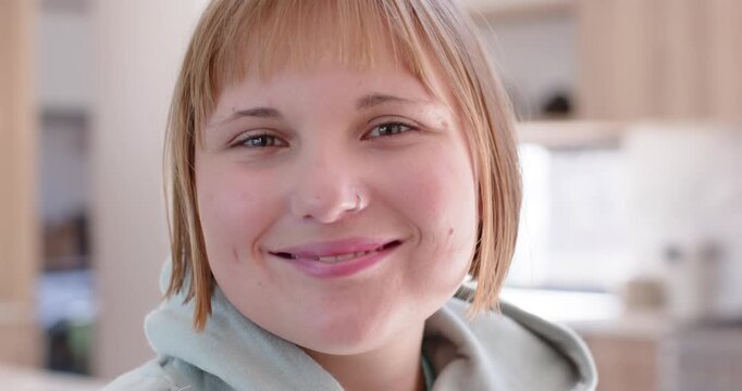 Female reacting to cue shifting soft smile into broad laugh tilting head in kitchen wearing hoodie