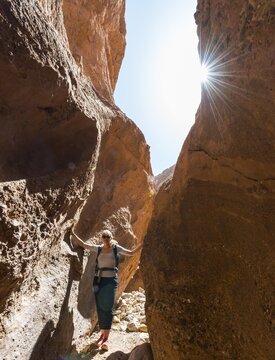 Young female hiker in a narrow sandstone canyon, solar reflex, Dades Valley, Morocco