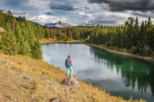 Young hiker at a lake, Fourth Lake, Valley of the Five Lakes, Jasper National Park, back mountains, Alberta, Canada