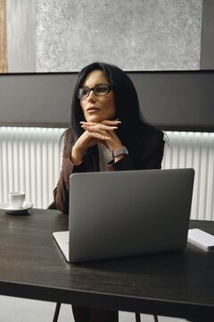 A divorce lawyer ponders strategy while sitting at a table in a modern office