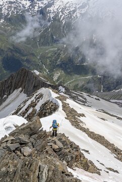 Mountaineer on a rocky ridge with snow, descent from the summit of the Sch&ouml;nbichler Horn, view of Tal Zemmgrund, Berliner H&ouml;henweg, Zillertal Alps, Tyrol, Austria
