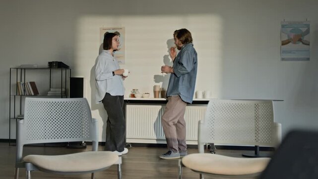 Caucasian young woman and Caucasian young man standing in counseling office, drinking coffee and talking during support group break. Video for mental health marketing campaigns