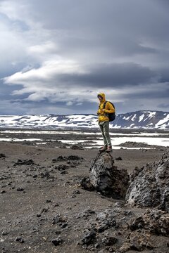 Hikers in snow-covered volcanic landscape with volcanic sand and petrified lava, crater of Askja volcano, Icelandic highlands, Iceland