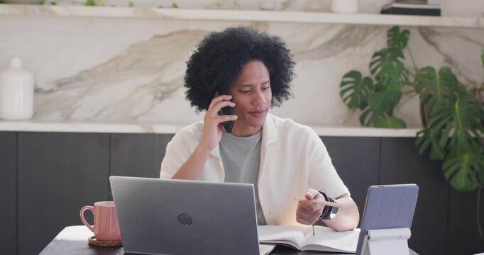 Phone ringing as African American adult man handling work call at home checking smartwatch  and  tab