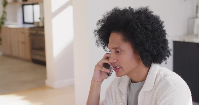 African American man taking call, referencing laptop and tablet, working at home, copy space