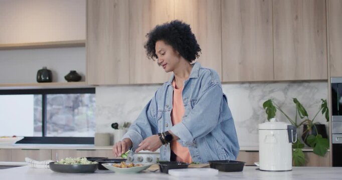 African American man scanning ingredients using tongs and filling black boxes for meals at island