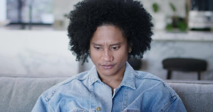 African American man in denim jacket working on laptop on living-room couch as camera pulling back