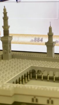 A close-up pan of a detailed architectural scale model of the Prophet's Mosque (Al-Masjid an-Nabawi) displayed at an Islamic exhibition.