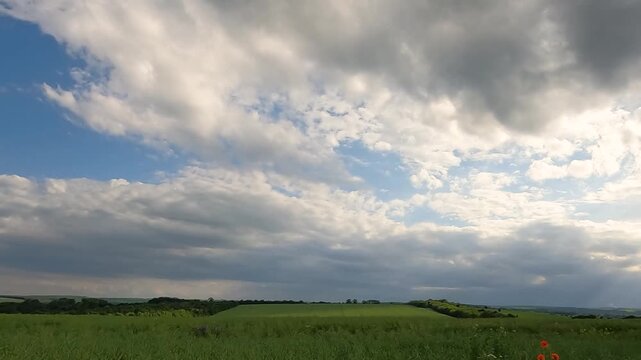 storm clouds over the field. green rapeseed field against the sky. sun rays over a green field. sun rays in dark clouds. Ukrainian landscape 4K
