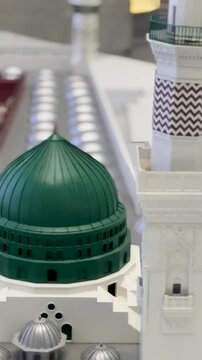 A detailed architectural scale model of the Prophet's Mosque (Al-Masjid an-Nabawi) featuring the iconic Green Dome and historic minarets.