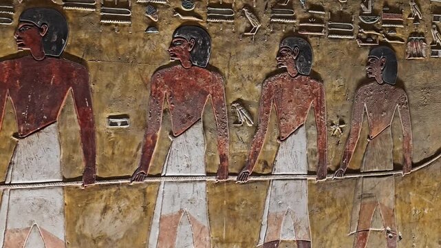 Close-up of ancient Egyptian relief carving inside KV17 tomb of Seti I, Valley of the Kings, Luxor, Egypt, showing a deity figure with black hair and deteriorating pigment.