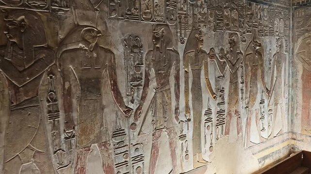 Close-up of ancient Egyptian relief carving inside KV17 tomb of Seti I, Valley of the Kings, Luxor, Egypt, showing a deity figure with black hair and deteriorating pigment.