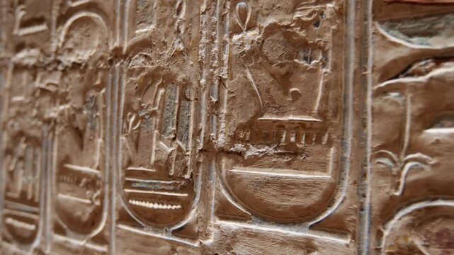 Close-up of golden hieroglyphic relief carvings inside KV17 tomb of Seti I, Valley of the Kings, Luxor, Egypt, showing detailed ancient Egyptian symbols, birds and sacred figures.
