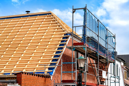 Renovation of a pitched roof with timber battens, roof membrane and scaffolding on a brick house