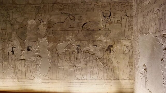 Close-up of ancient Egyptian relief carving inside KV17 tomb of Seti I, Valley of the Kings, Luxor, Egypt, showing a deity figure with black hair and deteriorating pigment.