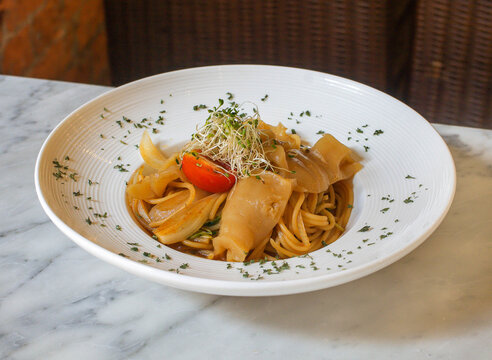Seafood pasta served with squid onions and rich savory sauce