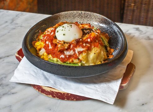 Baked vegetables topped with cheese and egg in a sizzling skillet Oven Baked Comfort Dish