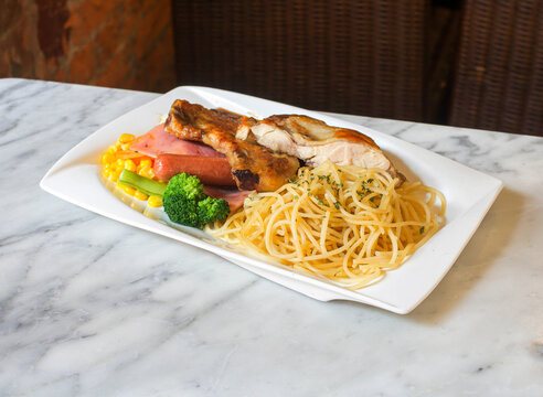 Grilled chicken served with pasta sausage vegetables and sweet corn for a complete meal