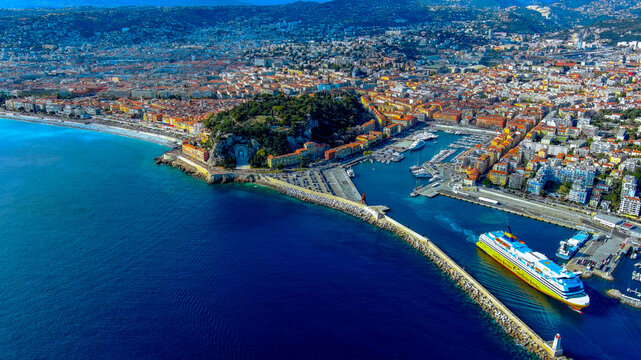 Aerial drone view of Nice Port Lympia with Corsica Ferries passenger ship docked at harbour and Ch&acirc;teau Hill behind, France
