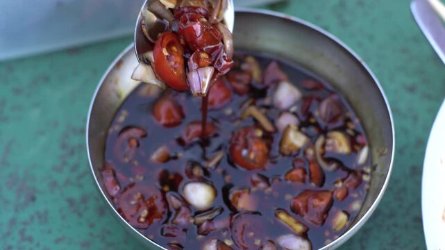 Sweet soy sauce chili sauce with sliced ​​red cayenne pepper, Spoonful of Savory Soy Sauce Dipping Dip with Fresh Chopped Tomatoes and Onions in a Bowl