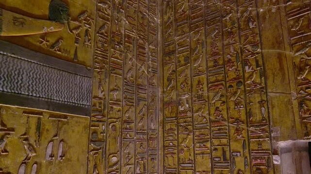 Close-up of ancient Egyptian relief carving inside KV17 tomb of Seti I, Valley of the Kings, Luxor, Egypt, showing a deity figure with black hair and deteriorating pigment.