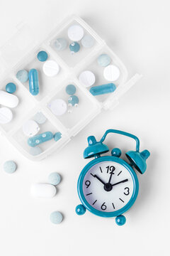 Top view of pill organizer and alarm clock on white background, Daily medication and supplement routine concept