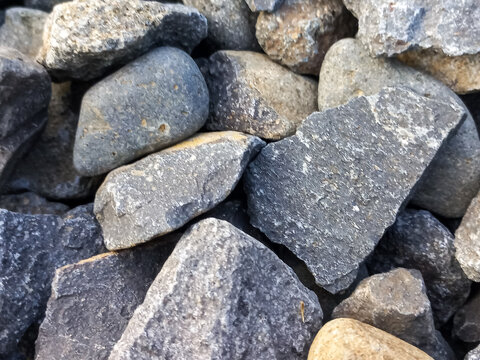 Close-up full frame shot of sharp and smooth crushed grey stones and pebbles mixed together.