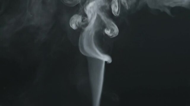 A thin stream of white smoke rises against a dark background