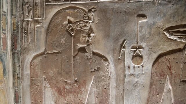 Close-up of ancient Egyptian relief carving inside KV17 tomb of Seti I, Valley of the Kings, Luxor, Egypt, showing a deity figure with black hair and deteriorating pigment.
