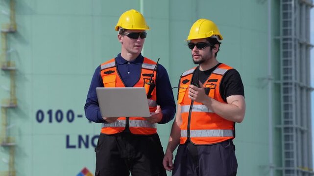 Engineer inspection industrial safety hard hat reflective vest laptop radio maintenance at refinery tank, male workers coordinate gas plant monitoring for natural gas storage and LNG terminal teamwork