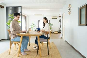 Fototapeta premium 自宅のテーブルでノートパソコンで作業をする若い日本人のパワーカップル