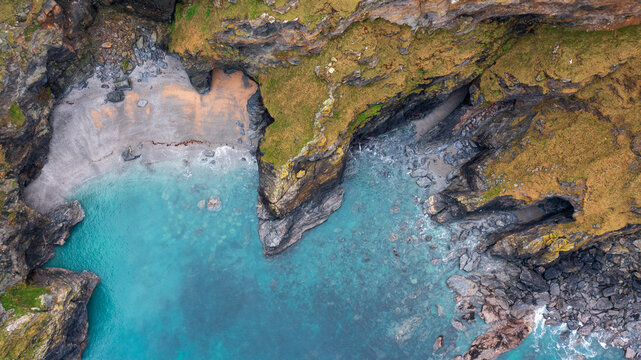 Aerial view of the rugged cliffs and turquoise waters at Hell's Mouth with a small secluded beach in Camborne, Cornwall, United Kingdom.