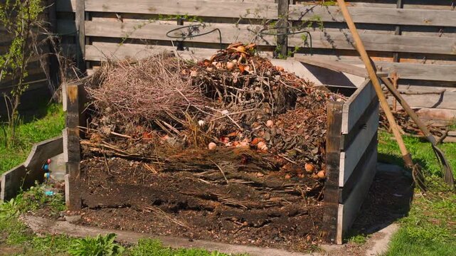 Wooden compost bin filled with organic garden waste in backyard