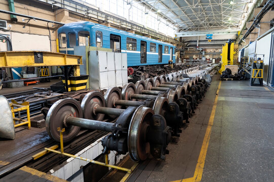 A blue train is positioned inside a large maintenance facility. Tools and materials are organized around the workshop, highlighting the industrial atmosphere of train repairs