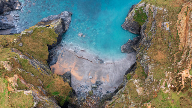 Aerial view of the rugged cliffs and turquoise waters of Hell's Mouth cove with its sandy beach and rocky shoreline in Camborne, Cornwall, United Kingdom.