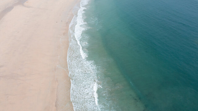 Aerial view of Harlyn Bay Beach with gentle white waves breaking on the sandy shore and turquoise ocean water Saint Merryn, Cornwall, United Kingdom.