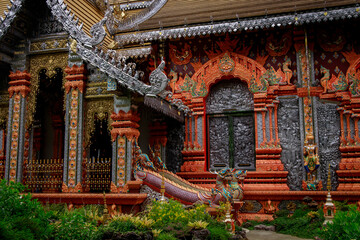 Fototapeta premium Beautiful architectural features of a classic thai temple embraced by vibrant lush greenery