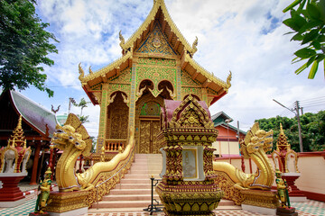 Obraz premium Intricate temple design featuring winding statues surrounded by vibrant greenery beneath a dramatic cloudy sky