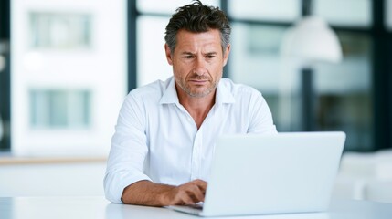 Fototapeta premium Mature man focusing on laptop screen in a modern office, working on business project or online learning