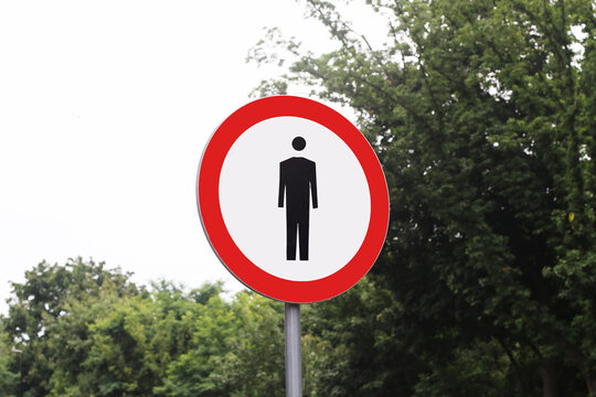 No pedestrian traffic sign on roadside pole. Public safety and access restriction background. Regulatory road symbol used to prohibit pedestrian entry in specific areas.