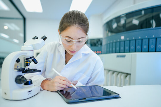 Clinical laboratory scientist recording experimental data into electronic lab notebook (ELN). Biobank manager tracking specimen inventory workflow via wireless LIMS tablet.