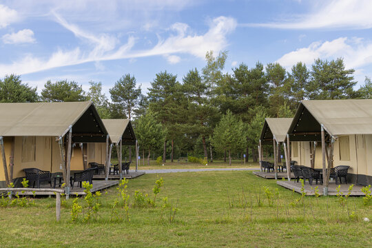 Glamping tents at a summer campground with wooden decks and forested background for outdoor relaxation