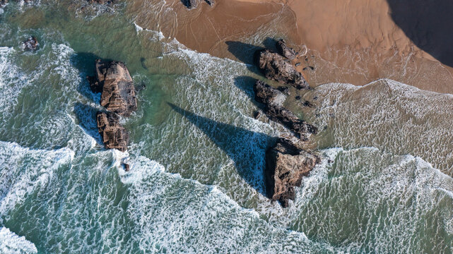 Aerial view of Bedruthan Steps sea stacks with waves crashing against the rocks and sandy beach in Padstow, Cornwall, United Kingdom.